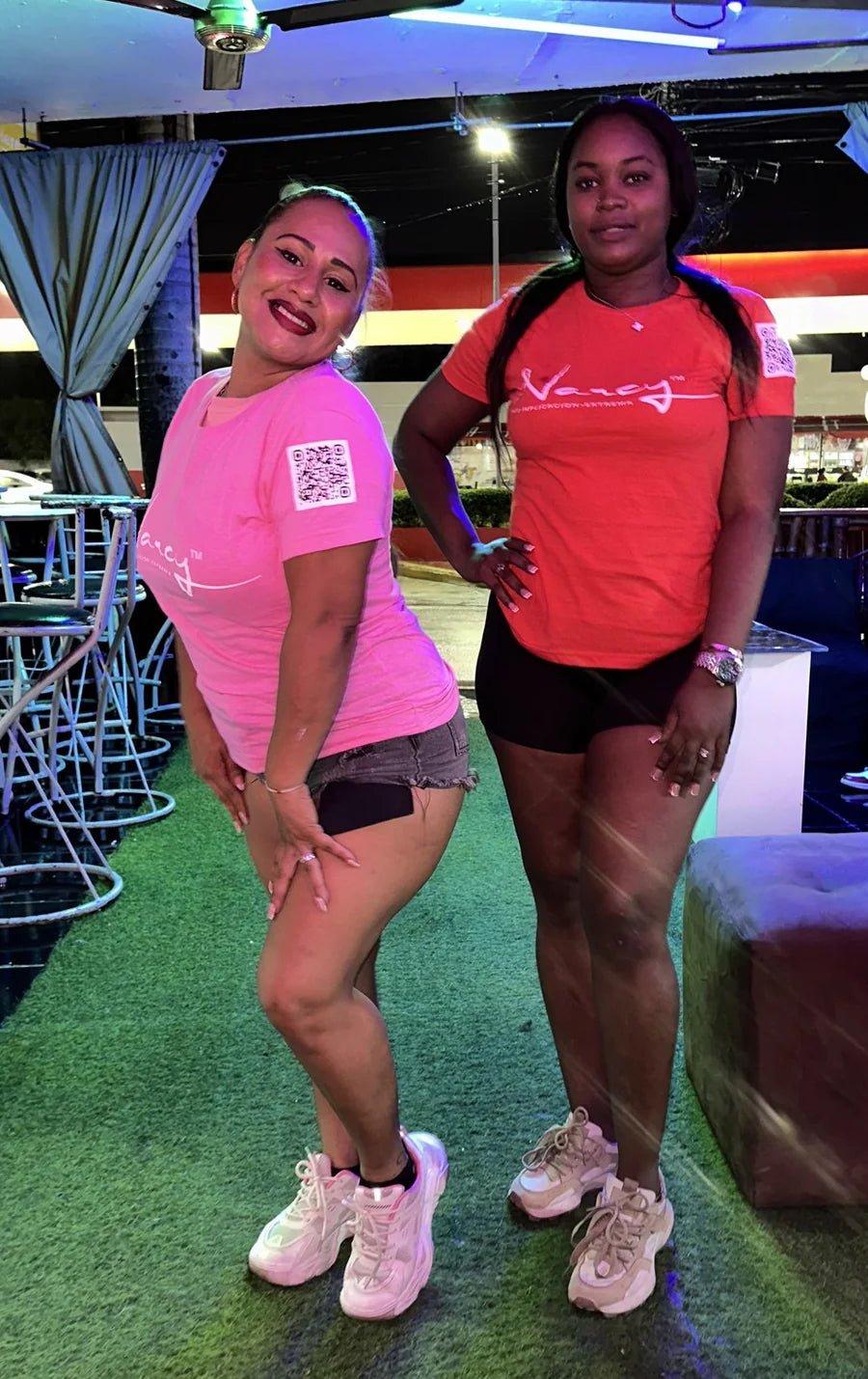 Two women wearing Narcy logo tees in a lounge setting